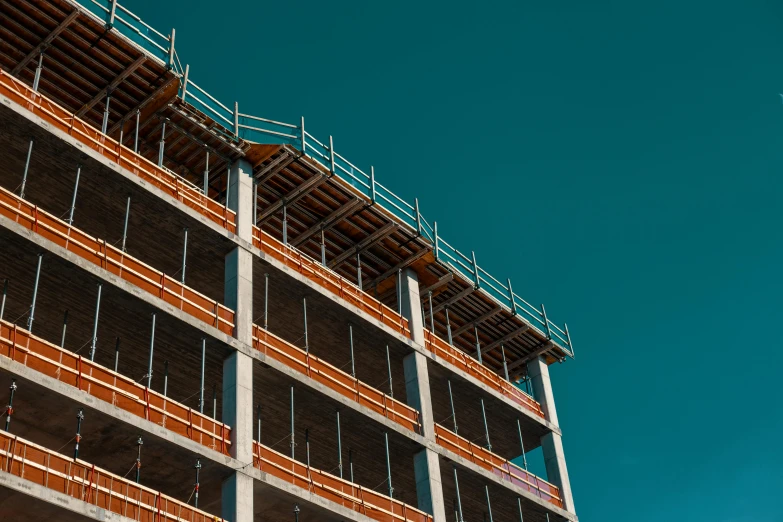 a building under construction with a blue sky in the background, a photo, by Lee Loughridge, unsplash, ten flats, side - view, promo image, desaturated