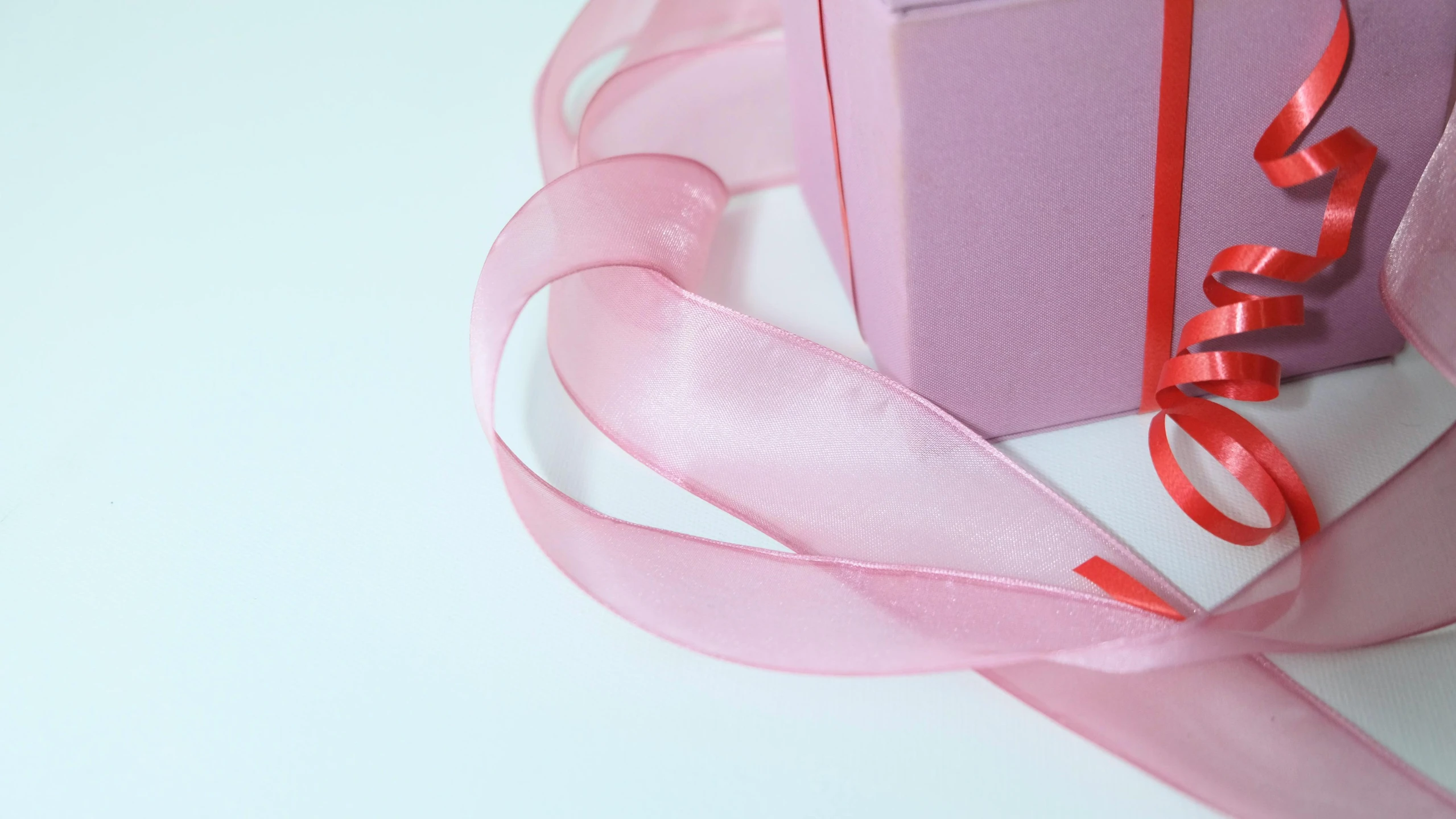 a pink gift box sitting on top of a white table, an album cover, trending on pexels, visual art, ribbon, translucent, closeup, hyperdetail