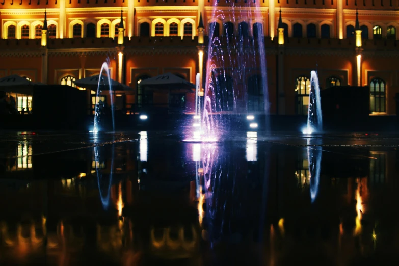 a fountain in front of a building lit up at night, by Julia Pishtar, pexels contest winner, fountains and arches, mall background, thumbnail, summer lighting