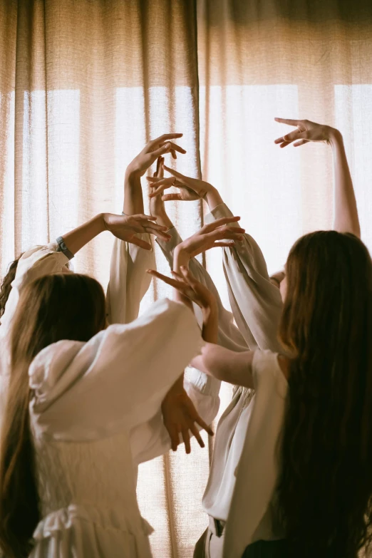 a group of women making a heart with their hands, an album cover, by Elsa Bleda, trending on pexels, renaissance, white and gold priestess robes, ballet pose, morning light, spirits covered in drapery