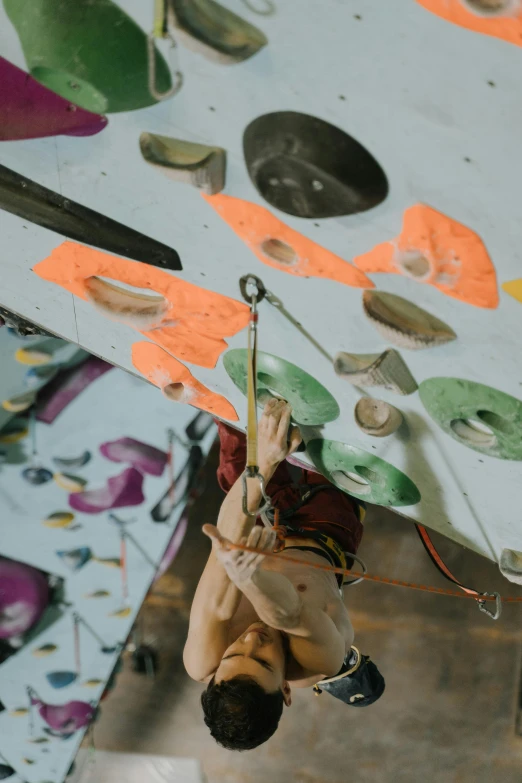 a man climbing up the side of a climbing wall, pexels contest winner, process art, things hanging from ceiling, in a workshop, top down shot, featured