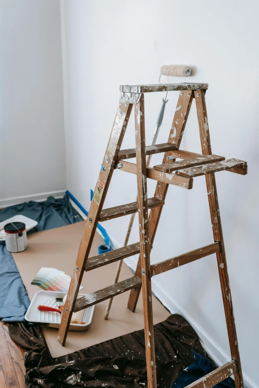 a ladder sitting on top of a hard wood floor, a painting, by Ben Zoeller, trending on pexels, under repairs, ilustration, set photograph, developers