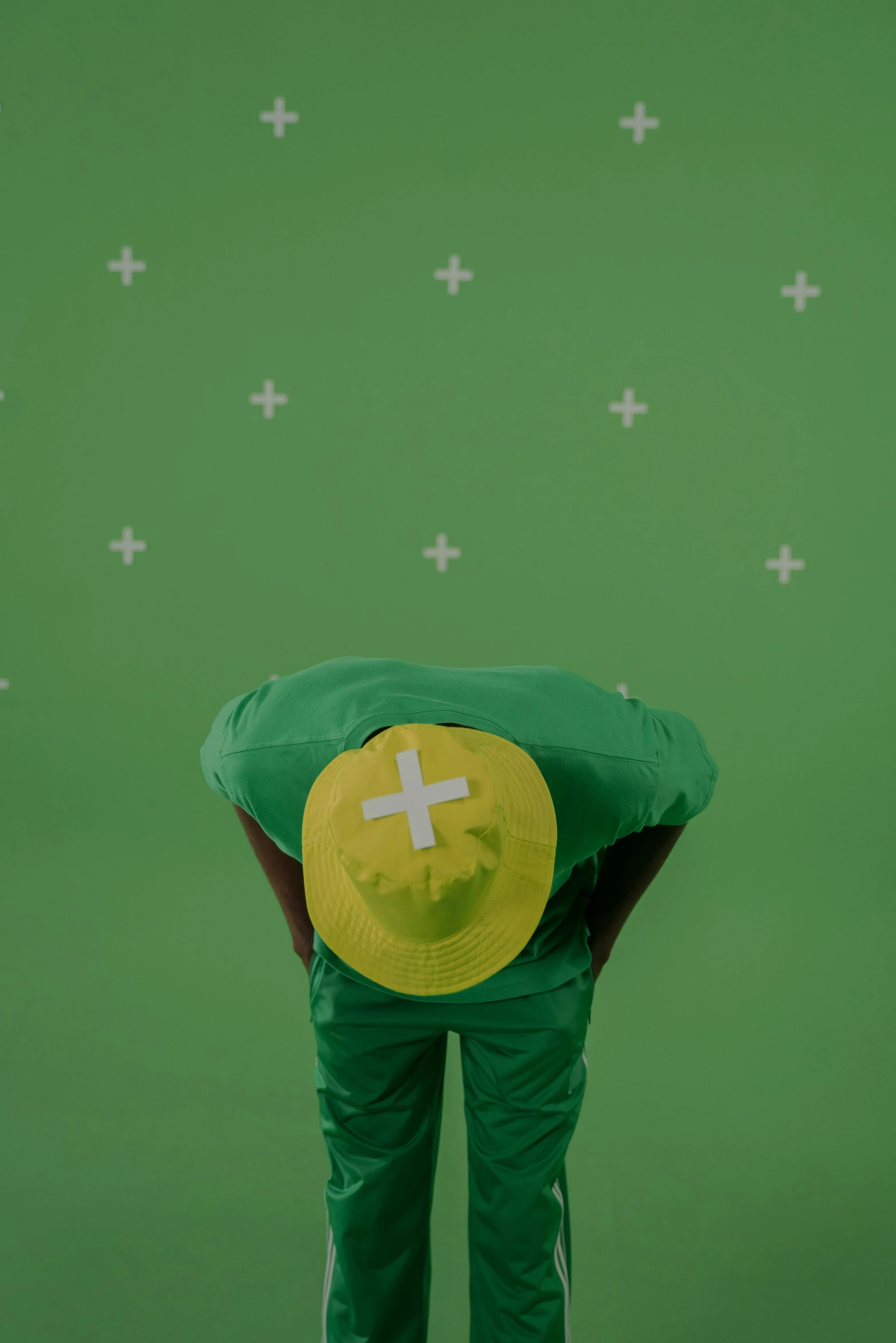 a man in green pants and a yellow hat, trending on unsplash, video art, looking exhausted, wearing a plug suit, backdrop, backfacing