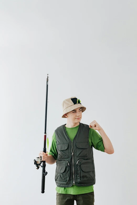 a boy in a green shirt is holding a fishing rod, an album cover, trending on pexels, wearing a vest, he is wearing a hat, full body with costume, sports photo