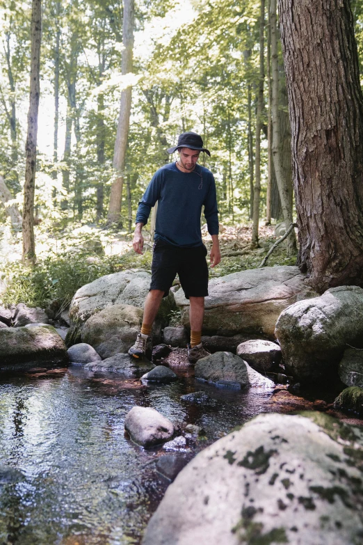 a man standing on a log over a stream, gray shorts and black socks, rhode island, 2019 trending photo, 2 5 6 x 2 5 6 pixels