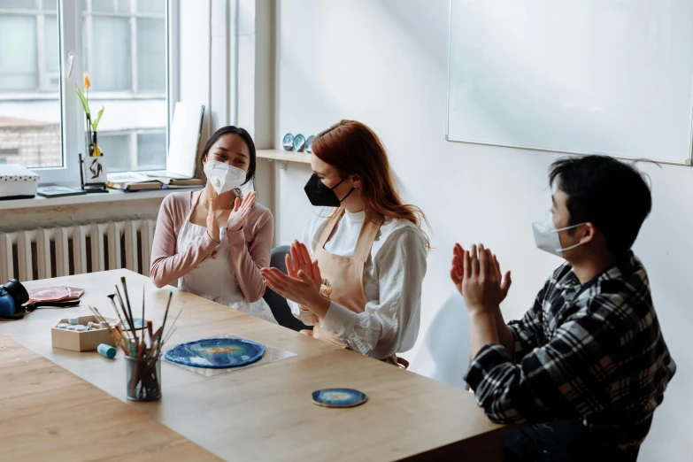 a group of people sitting around a wooden table, a hyperrealistic painting, pexels contest winner, wearing facemask, waving, profile image, white