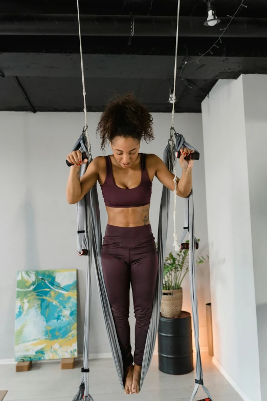 a woman standing on a hammock in a room, wearing fitness gear, afro tech, curated collections, studio picture