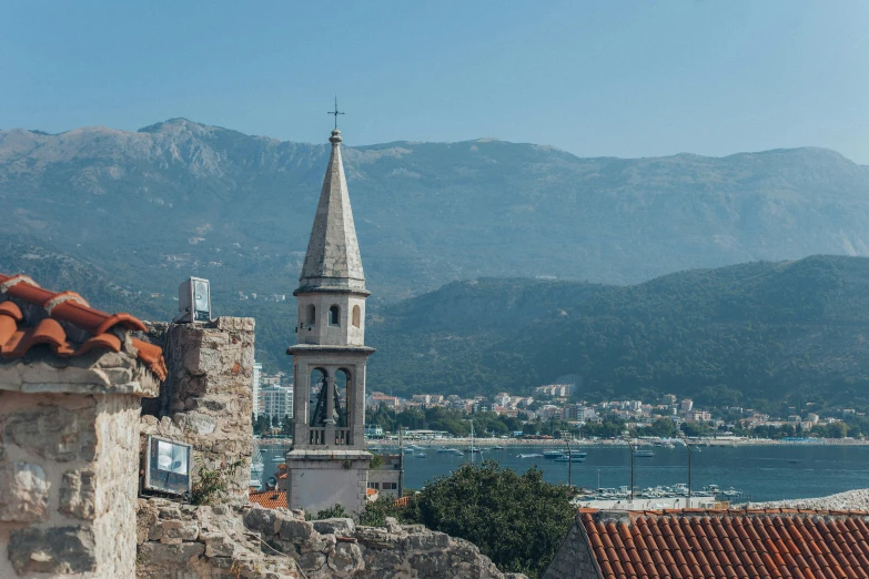 a clock tower on top of a building next to a body of water, pexels contest winner, baroque, mountains and ocean, byzantine ruins, boka, city views