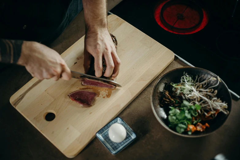 a person cutting up a piece of meat on a cutting board, by Nick Fudge, pexels contest winner, sōsaku hanga, sitting on a table, lachlan bailey, japanese collection product, thumbnail
