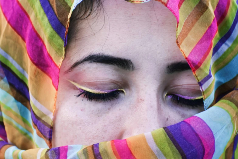 a close up of a person wearing a colorful scarf, trending on pexels, hyperrealism, winged eyeliner, middle eastern, stripe over eye, her eyes are closed