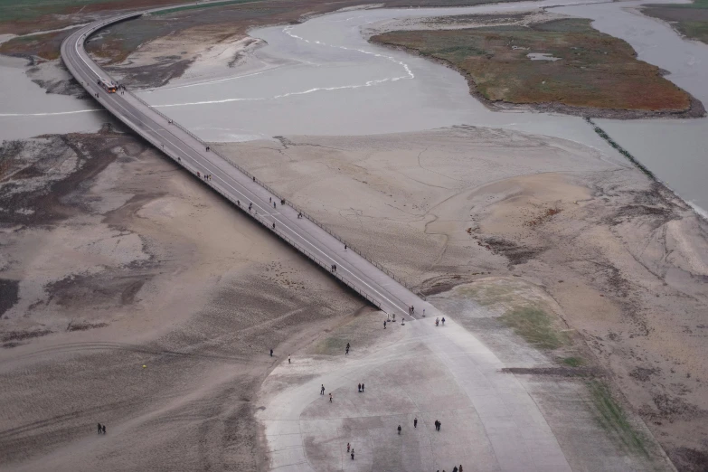 an aerial view of a bridge over a body of water, an album cover, by Thomas de Keyser, unsplash, land art, people fleeing, dry river bed, ignant, people walking into the horizon