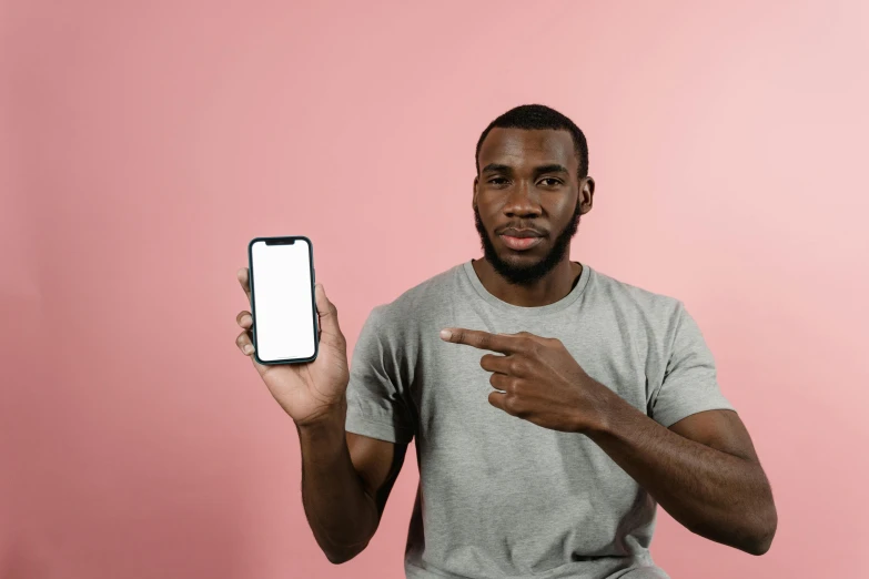 a close up of a person holding a cell phone, trending on pexels, realism, brown skin man egyptian prince, with pointing finger, wearing a muscle tee shirt, product introduction photo