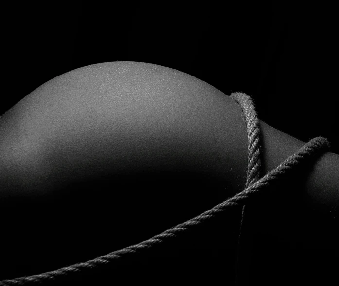 a black and white photo of a woman's breast, inspired by Robert Mapplethorpe, unsplash, conceptual art, rope, black canvas, set photo, sergey krasovskiy