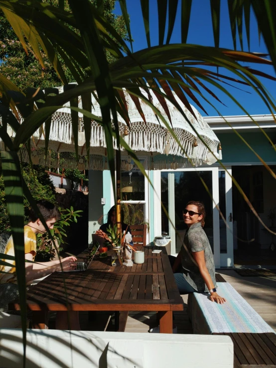 a person sitting at a table with a surfboard, house kitchen on a sunny day, with potted palm trees, te pae, profile image