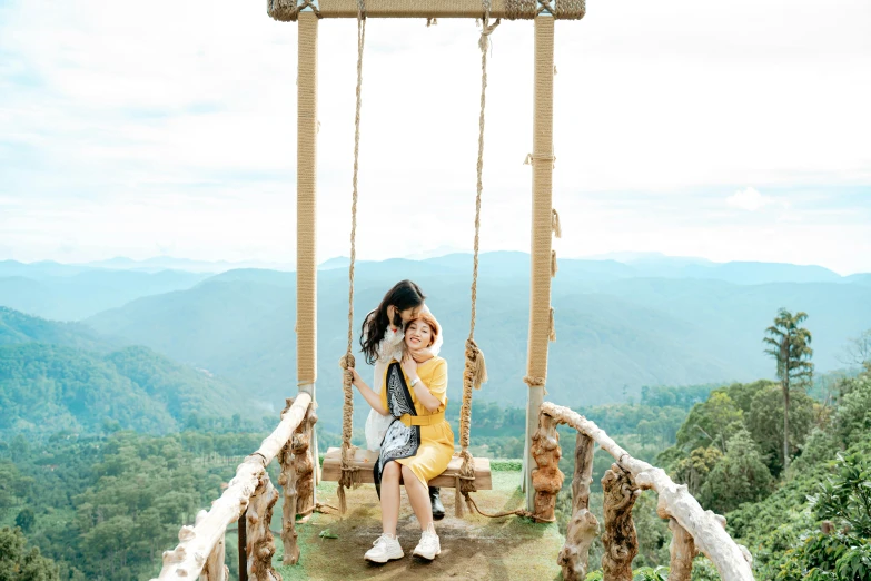 a girl sitting on a swing at the top of a mountain, a portrait, by Julia Pishtar, pexels contest winner, sumatraism, woman holding another woman, 😭 🤮 💕 🎀, in avila pinewood, avatar image