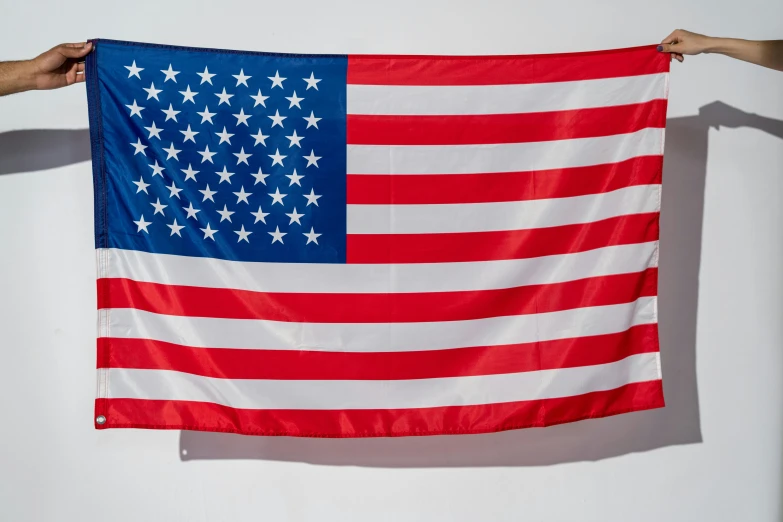 two hands holding an american flag against a white wall, a portrait, unsplash, ultrawide image, fan favorite, three - quarter view, facing front