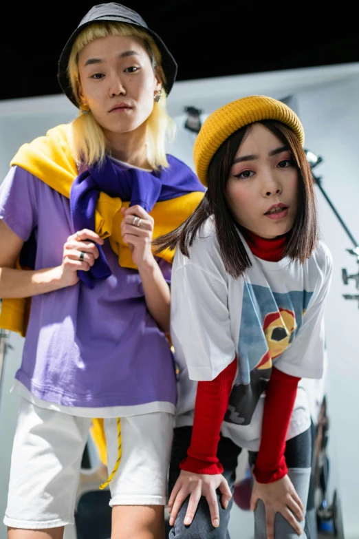 a couple of women standing next to each other, by Miyamoto, trending on pexels, realism, yellow purple, japanese streetwear, in tshirt, offwhite