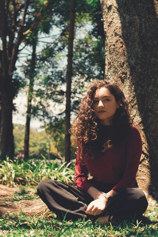 a woman sitting on the ground next to a tree, an album cover, pexels contest winner, curly dark hair, in sao paulo, hana alisa omer, profile image