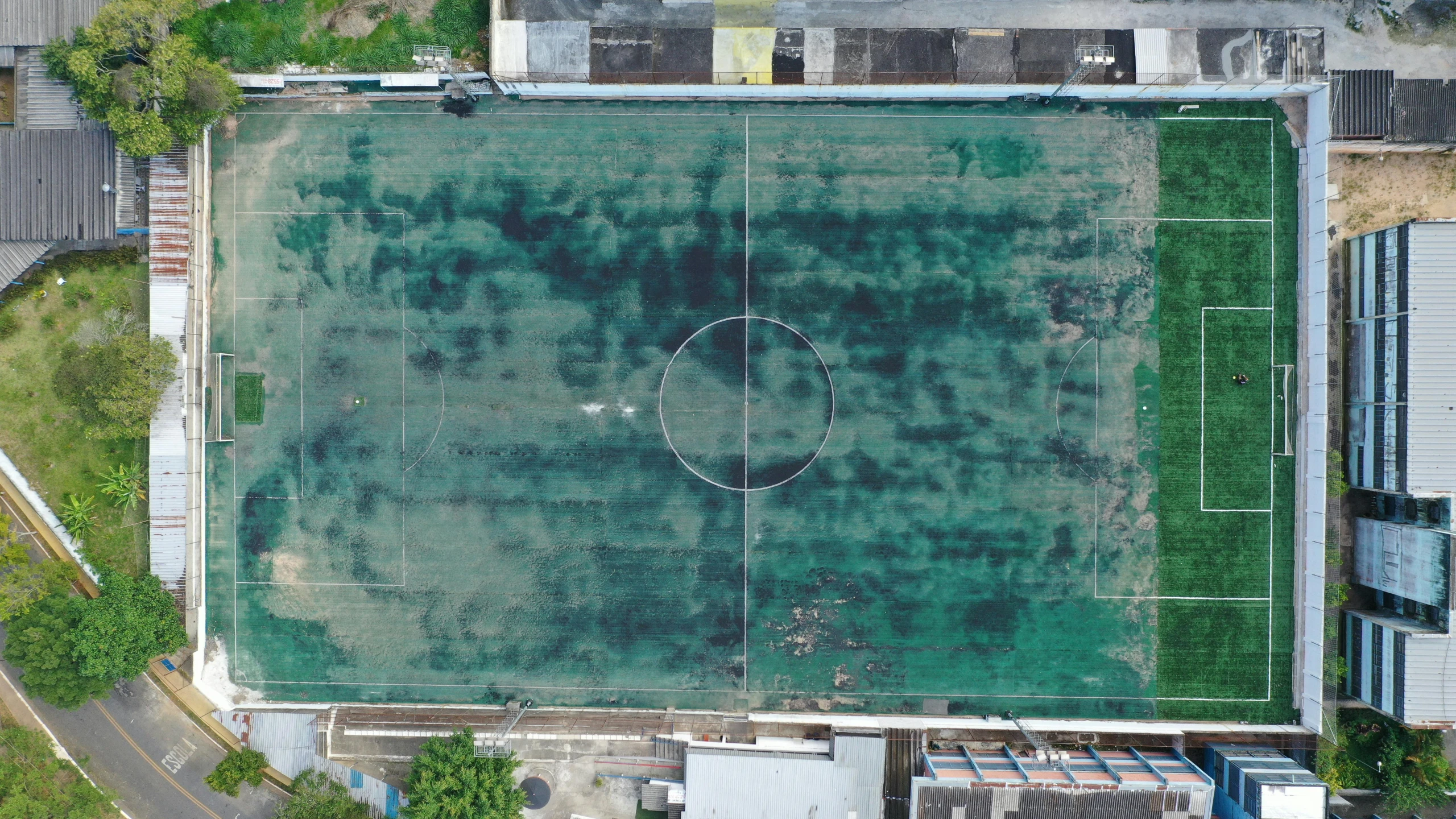 an aerial view of a soccer field surrounded by buildings, by Attila Meszlenyi, grungy, large scale photo