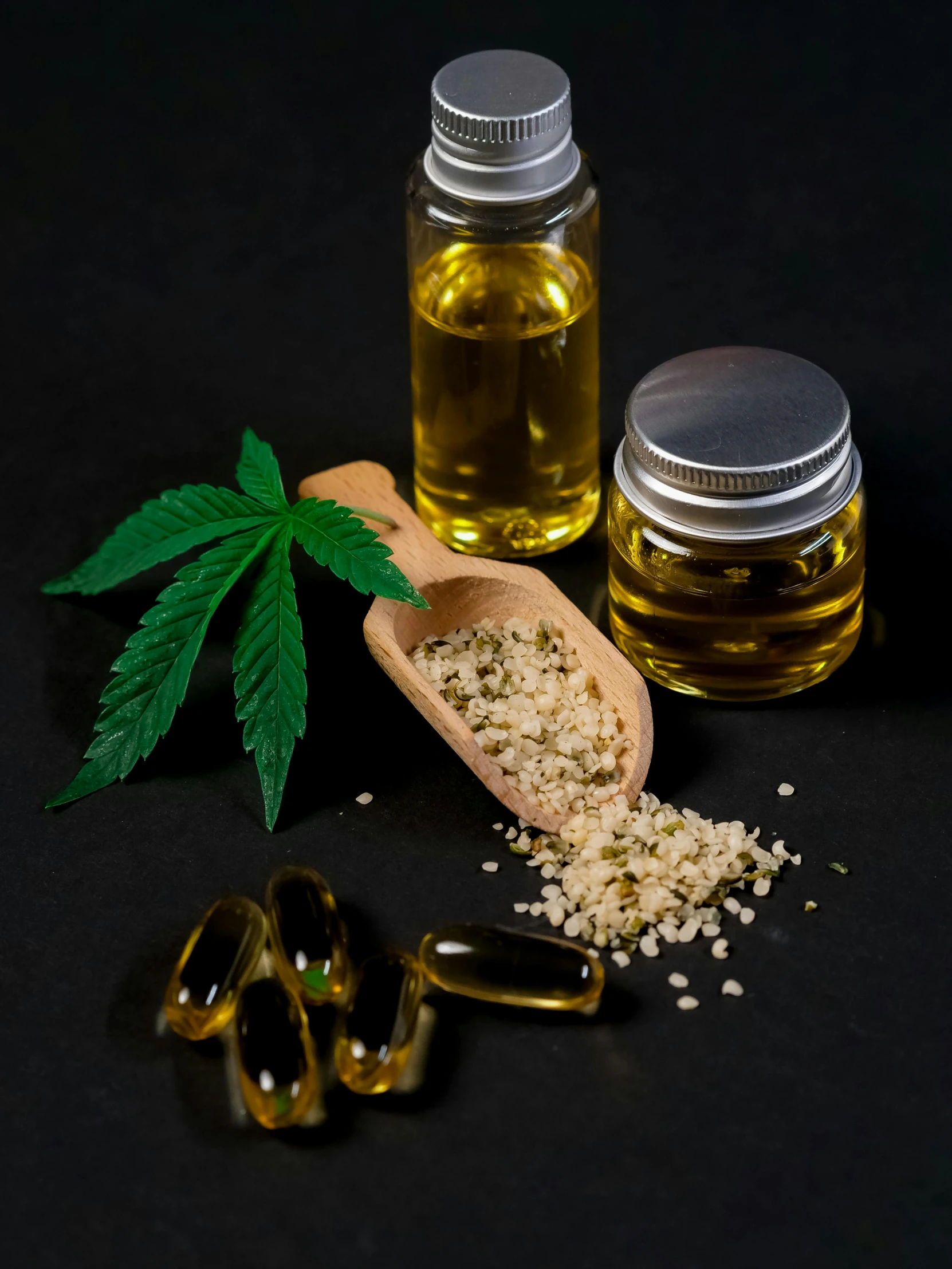 a wooden spoon sitting next to a bottle of hemp oil, a picture, by Julia Pishtar, shutterstock, on a black background, 4 cannabis pots, open synthetic maw, high detail product photo