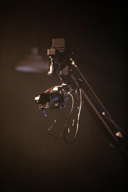 a close up of a camera on a tripod, by David Donaldson, theatrical lighting, with a robotic arm, concert light, high angle shot