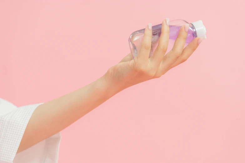 a close up of a person holding a bottle of liquid, by Olivia Peguero, aestheticism, pink background, background image, profile image, transparent body