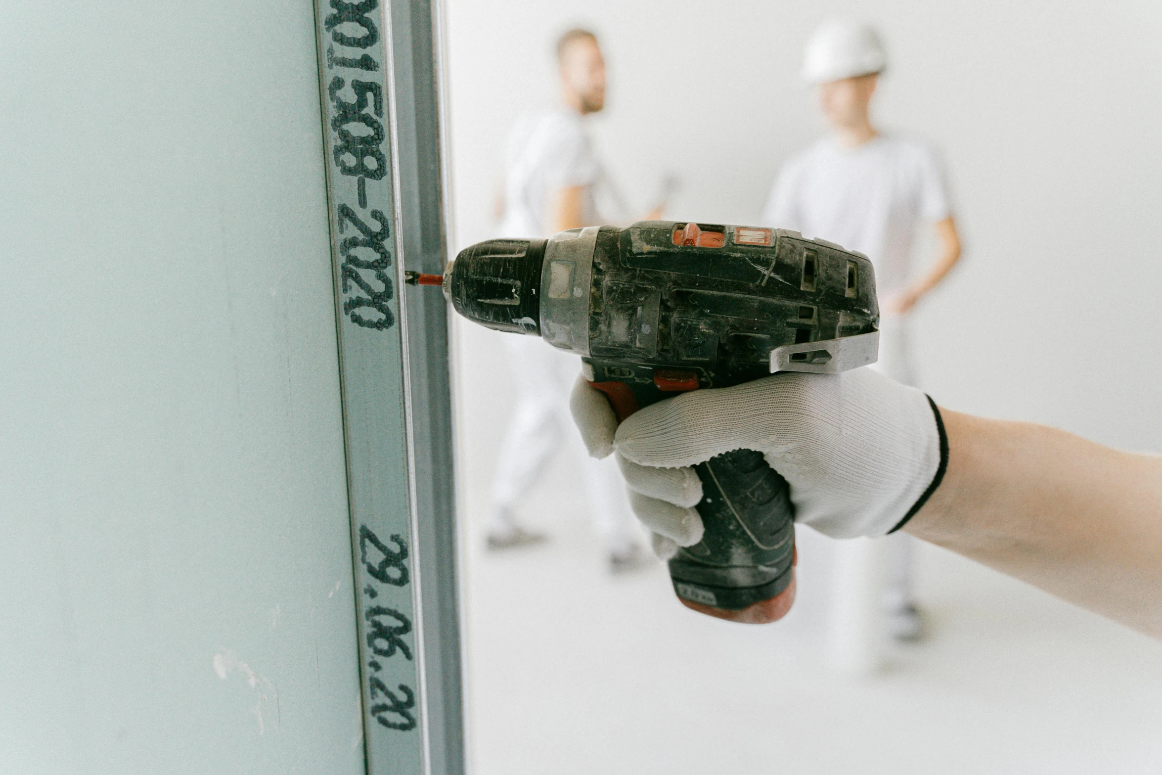 a close up of a person holding a drill, white building, panel, metal readymade, white walls