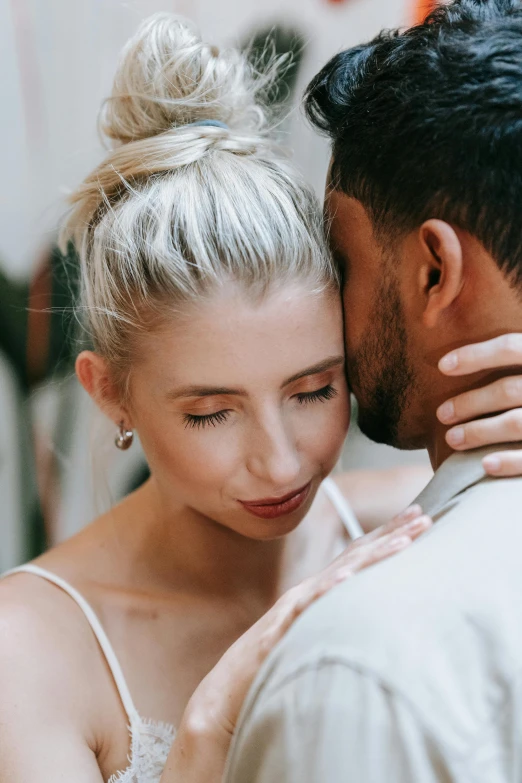 a man and a woman standing next to each other, a photo, by Sara Saftleven, trending on unsplash, hair styled in a bun, intimate holding close, editorial model, groom