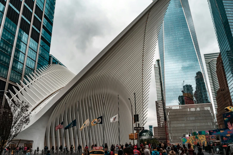 a crowd of people walking across a street next to tall buildings, inspired by Zaha Hadid, pexels contest winner, art nouveau, white sweeping arches, mta subway entrance, calatrava, gopro photo