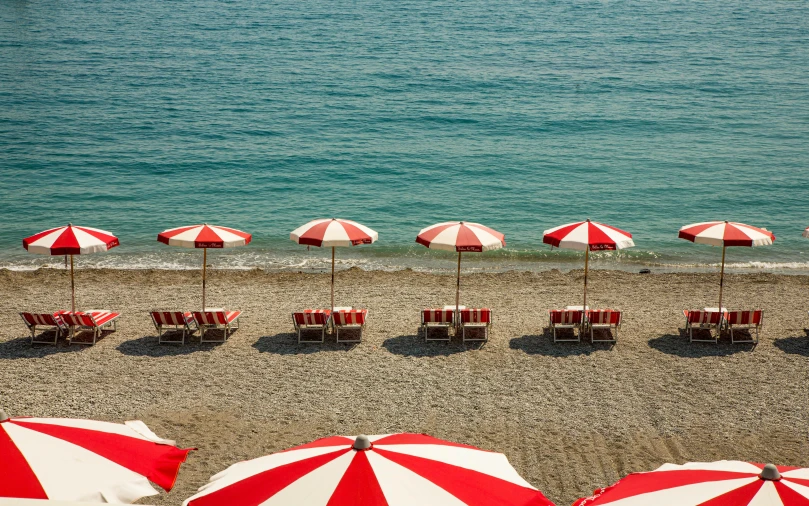 a beach filled with lots of red and white umbrellas, by Carlo Martini, epicurious, fan favorite, wes anderson and gucci, payne's grey and venetian red