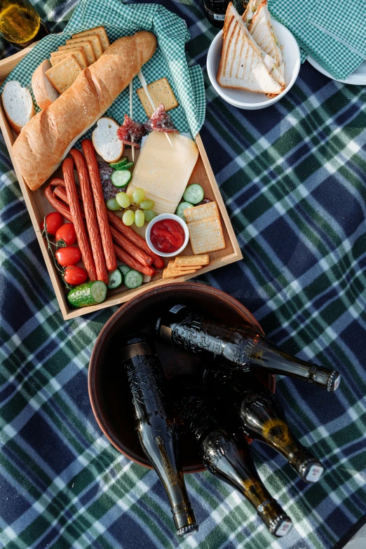 a table topped with plates of food next to a bottle of wine, dau-al-set, picnic, hotdogs, square, no crop