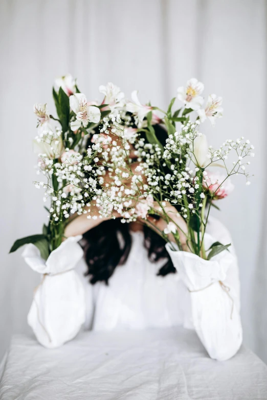 a woman covering her face with a bunch of flowers, by Lucia Peka, light cream and white colors, with a spine crown, in front of white back drop, high light on the left