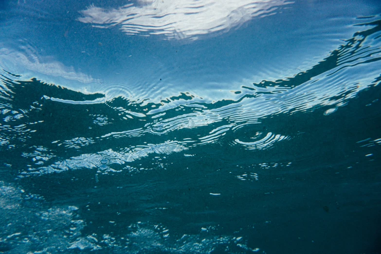 a man riding a wave on top of a surfboard, an album cover, unsplash, underwater bubbles, blue reflections, subsurface scandering, currents