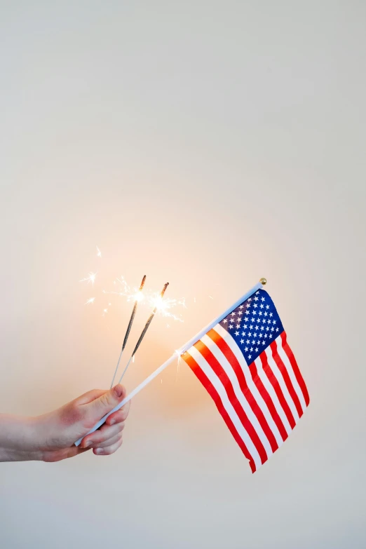 a person holding an american flag and sparklers, mint, plain background, instagram post, flags