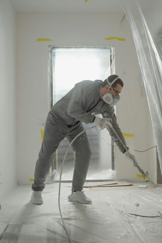 a man that is standing in the middle of a room, an airbrush painting, dust mask, white, grey, carpenter