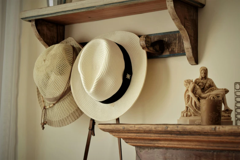 a couple of hats sitting on top of a shelf, a still life, inspired by Christopher Wood, unsplash, arts and crafts movement, silver，ivory, sun - drenched, rustic wood, wearing a fedora