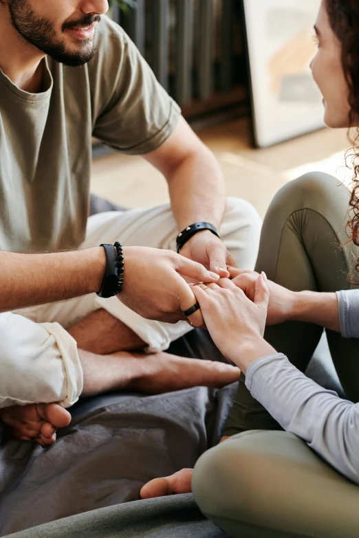 a man putting a ring on a woman's finger, bringing people together, sitting on a couch, laying down with wrists together, mental health