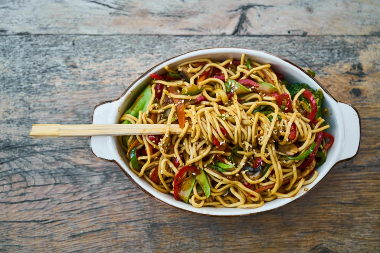 a white bowl filled with noodles and vegetables, by Julia Pishtar, chopsticks, a wooden, high quality upload, rectangle