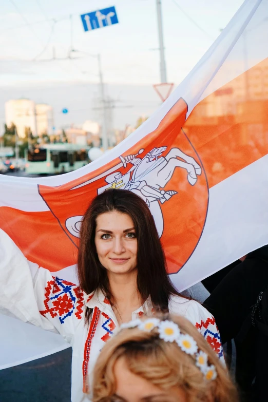 a woman is holding an orange and white flag, pexels contest winner, stuckism, rostov city, white and orange breastplate, 🚿🗝📝, profile image