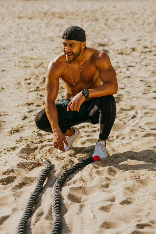 a man kneeling on top of a sandy beach, rubber hose style, fit physique, portrait of danny gonzalez, snacks