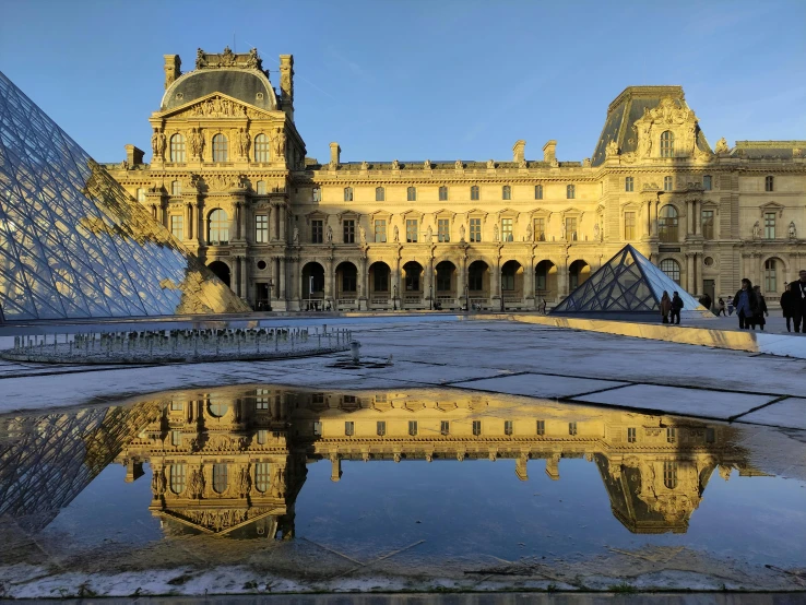 a reflection of a building in a puddle of water, a photo, inspired by Édouard Detaille, unsplash contest winner, renaissance, on display in the louvre, slide show, square, seen from outside