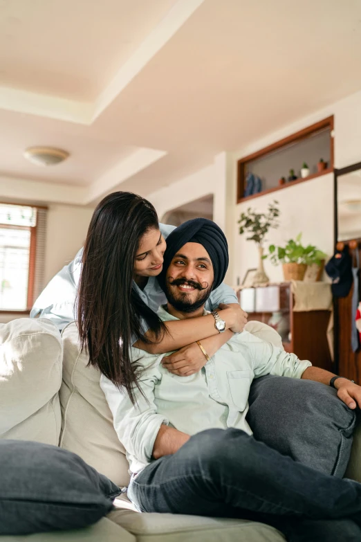 a man and a woman sitting on a couch, inspired by Manjit Bawa, pexels contest winner, hugging each other, playful smirk, india, australian