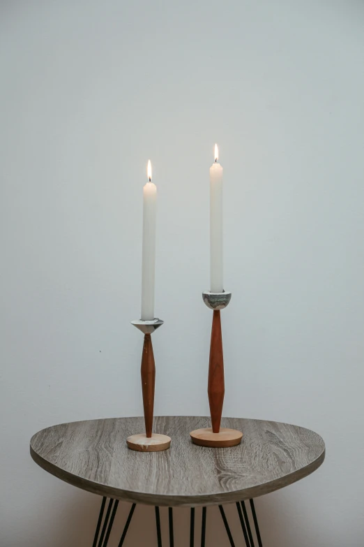a couple of candles sitting on top of a table, inspired by Constantin Hansen, woodturning, silver light, medium long shot, cedar