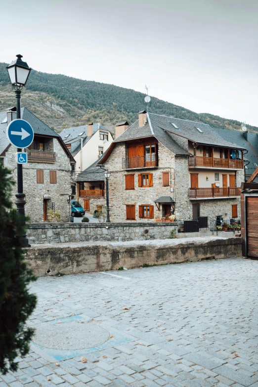 a cobblestone street with a mountain in the background, inspired by Valéria Dénes, trending on unsplash, les nabis, houses on stilts, square, french village exterior, taken in the mid 2000s