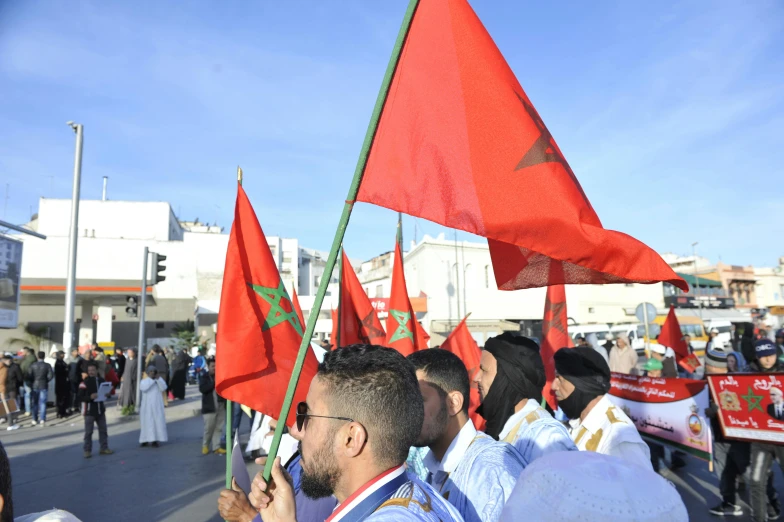 a group of people walking down a street holding flags, a photo, hurufiyya, red banners, square, professional image