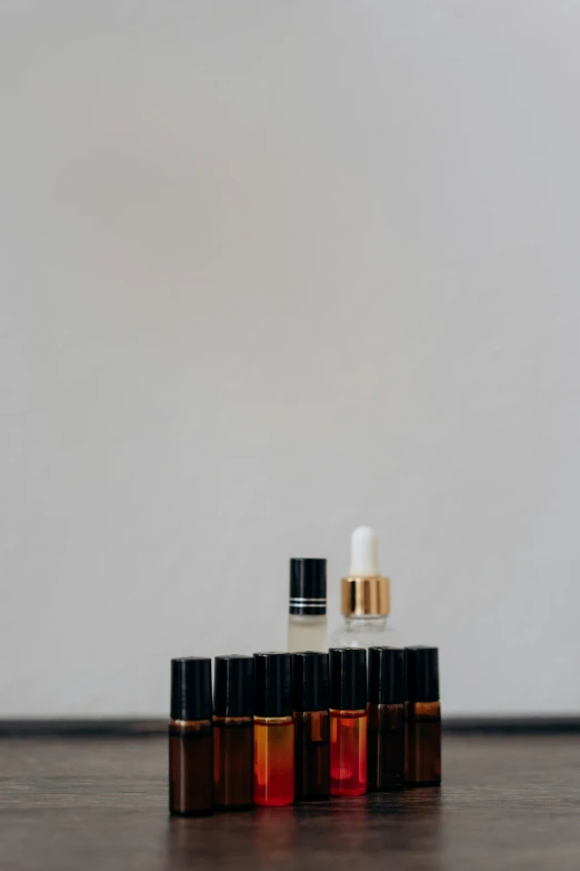 a couple of bottles sitting on top of a wooden floor, a picture, by Gavin Hamilton, unsplash, minimalism, vials, red black and gold color scheme, miniature product photo, black on white