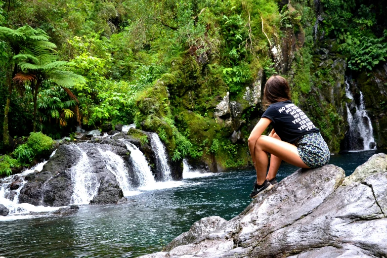 a woman sitting on a rock in front of a waterfall, reunion island landscape, instagram photo, st cirq lapopie, gazing at the water