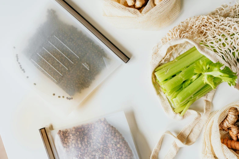 a couple of bags of food sitting on top of a table, a still life, trending on pexels, sustainable materials, background image, greens, recipe