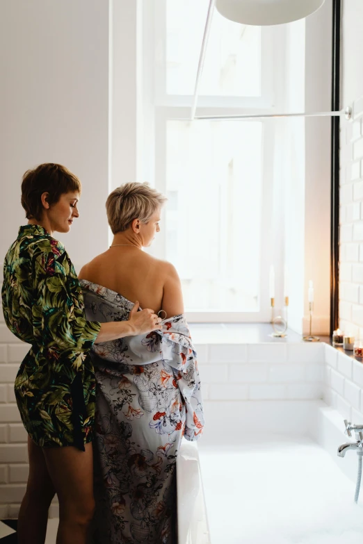 a couple of women standing next to each other in a bathroom, by Matija Jama, pexels contest winner, art nouveau, hygge, showing her shoulder from back, wearing pajamas, scandinavian