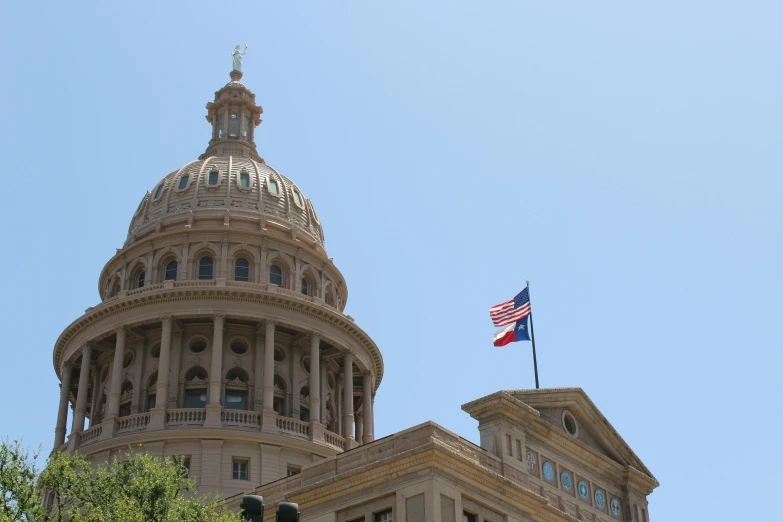 a large building with a flag on top of it, a photo, by Carey Morris, pexels, the texas revolution, 2 5 6 x 2 5 6 pixels, elden ring capitol, view from bottom to top